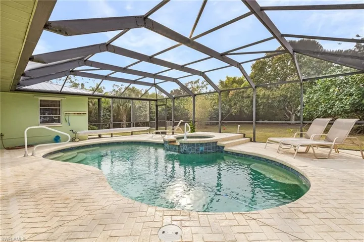 View of swimming pool featuring an in ground hot tub, glass enclosure, and a patio area