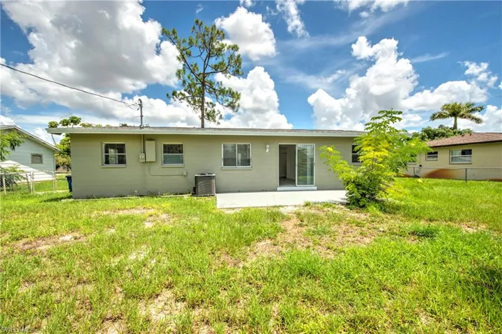 Rear view of property featuring central air condition unit, a lawn, and a patio area
