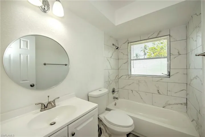 Full bathroom with tiled shower / bath combo, toilet, and vanity