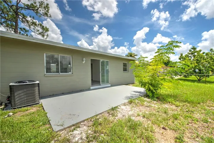 Rear view of property featuring central air condition unit, a patio area, and a lawn