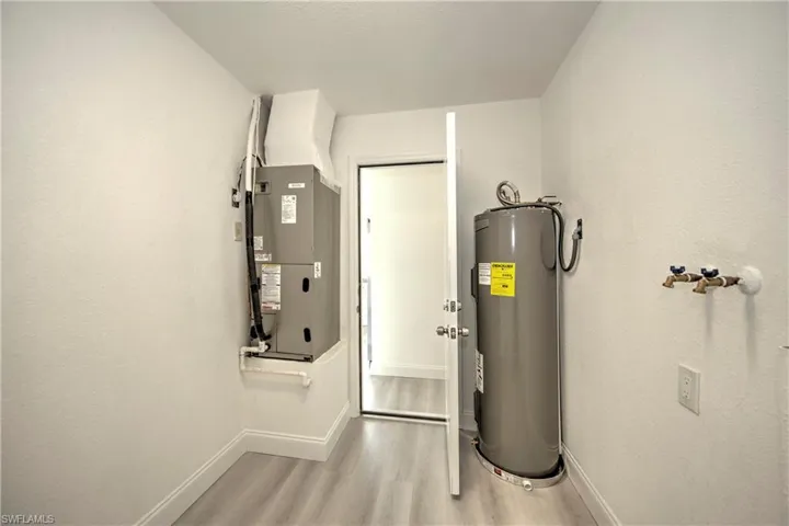 Utility room featuring water heater and heating unit