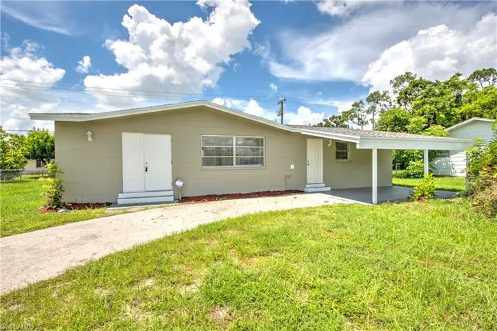Back of house featuring a lawn and a carport