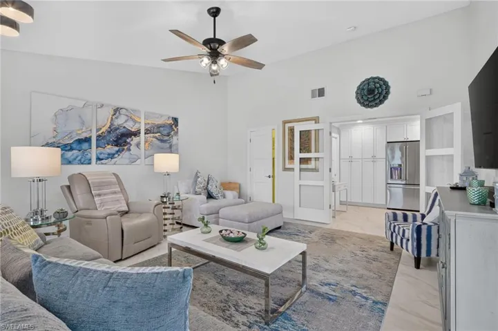 Spacious living area featuring high ceilings, a ceiling fan with integrated lighting, and light-toned flooring