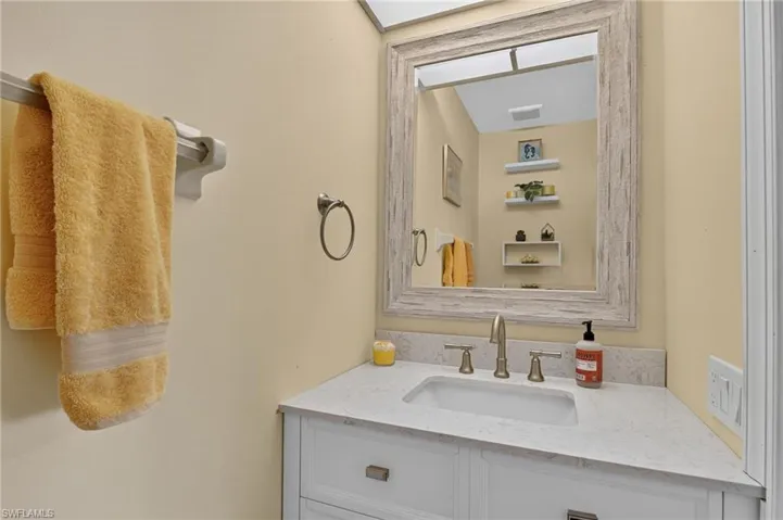 Bathroom vanity featuring a quartz countertop, integrated sink, and brushed nickel fixtures