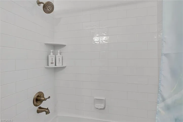 Subway tile shower surround with integrated corner shelves and bronze fixtures