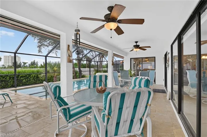 Expansive covered lanai with tile flooring, ceiling fans, and large sliding glass doors opening to the resort-style pool area