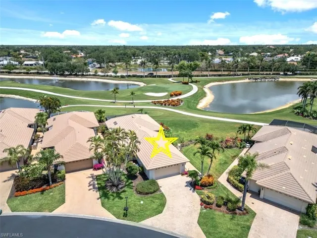 Aerial view of residential area featuring a golf course and a large body of water
