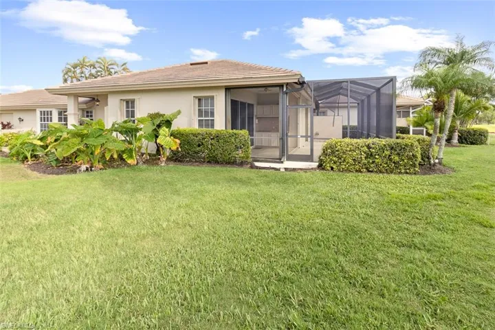 Back of house featuring stucco siding, a yard, a tile roof, and glass enclosure