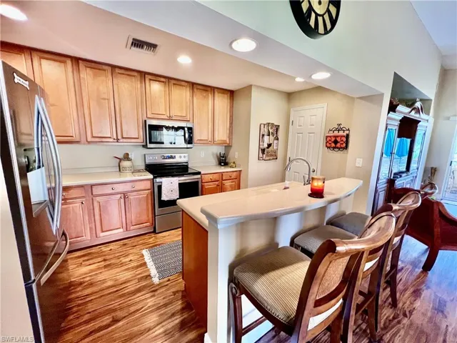 Kitchen featuring light wood-type flooring, a breakfast bar, a sink, and stainless steel appliances