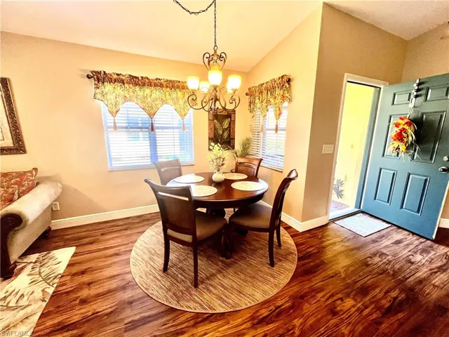 Dining room featuring baseboards, vaulted ceiling, wood finished floors, and an inviting chandelier