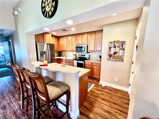 Kitchen with dark wood-style flooring, a kitchen breakfast bar, and appliances with stainless steel finishes