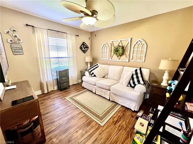 Den with luxury vinyl plank floors and ceiling fan