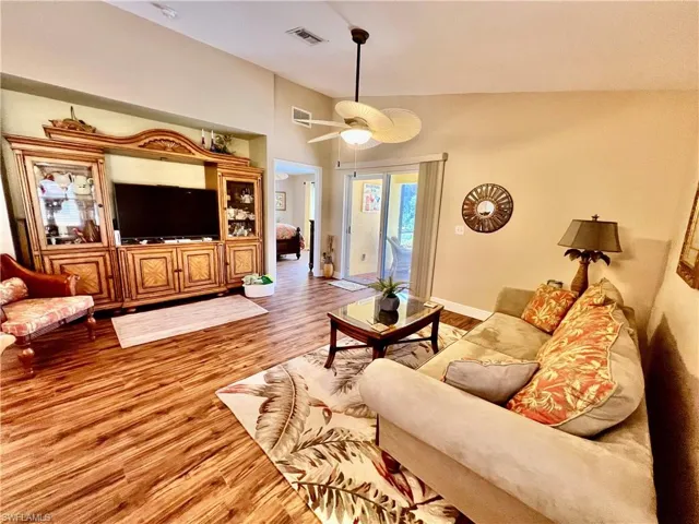 Living room featuring baseboards, ceiling fan, visible vents, and wood finished floors