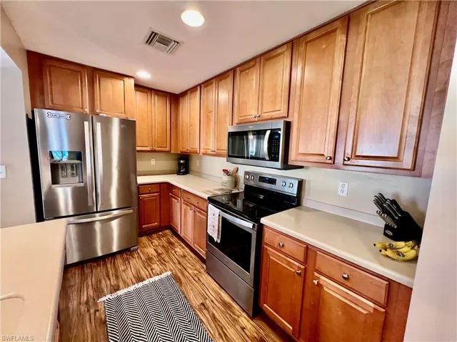 Kitchen featuring light countertops, light wood-type flooring, recessed lighting and appliances with stainless steel finishes