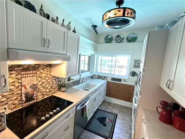 Kitchen featuring dishwasher, white cabinets, and range