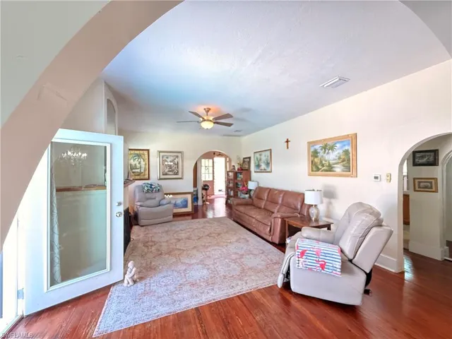 Living area with arched walkways, wood finished floors, and ceiling fan