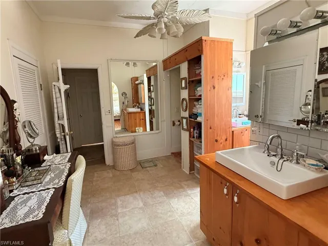 Bathroom with vanity, a ceiling fan, ornamental molding, and tasteful backsplash