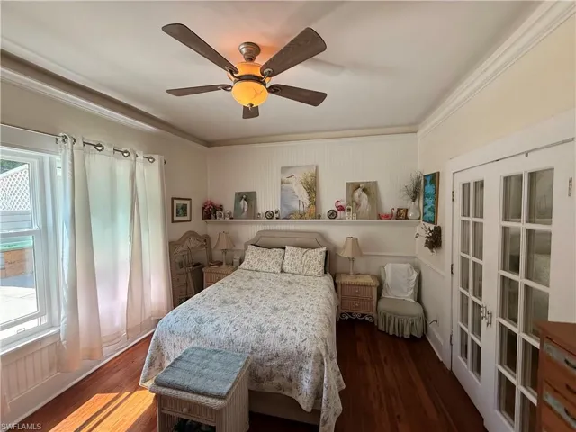 Bedroom with dark wood finished floors, a ceiling fan, and crown molding