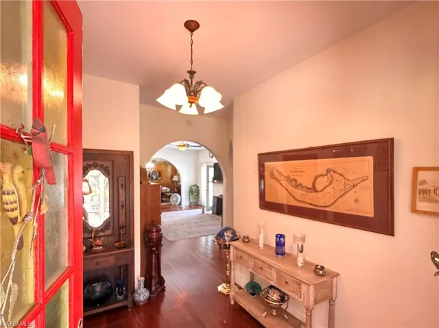 Foyer entrance featuring a chandelier, arched walkways, and dark wood-style floors