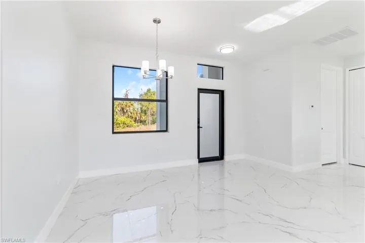 Unfurnished room featuring light marble finish flooring and a chandelier