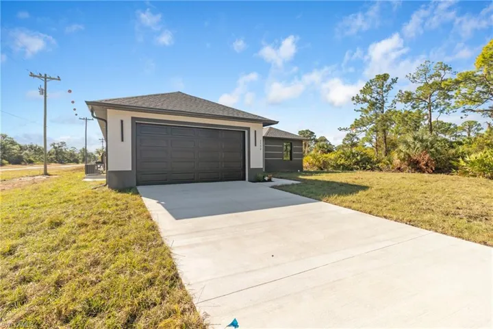 View of front of home with a front lawn, stucco siding, roof with shingles, and concrete driveway