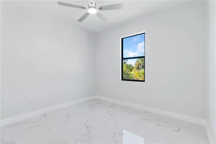 Spare room with marble look tiles and ceiling fan
