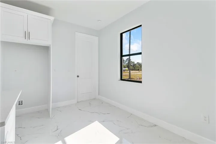 Unfurnished bedroom with baseboards and light marble finish floors