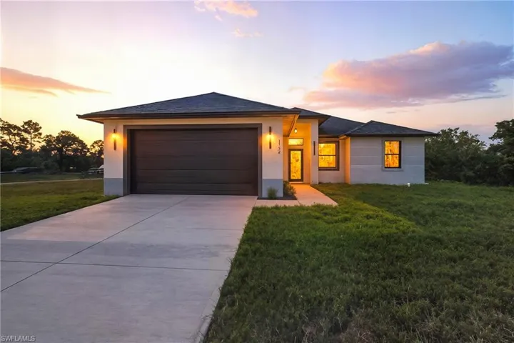 Prairie-style home featuring a yard, stucco siding, driveway, and an attached garage