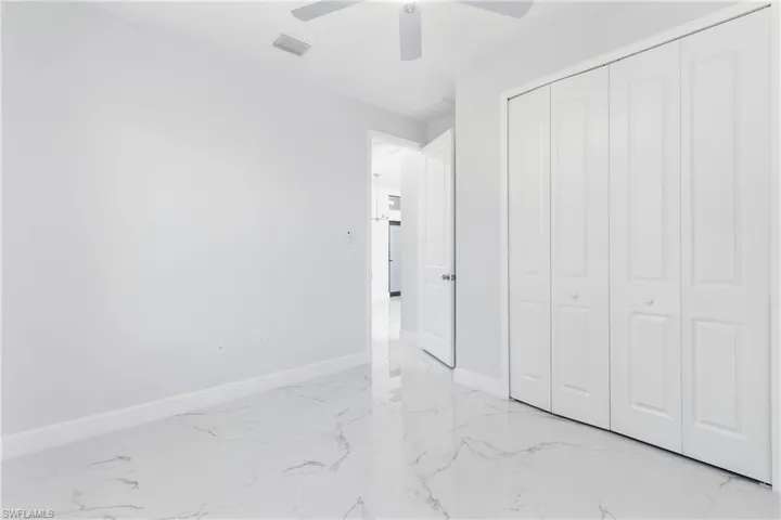 Unfurnished bedroom featuring light marble finish floors, ceiling fan, and a closet