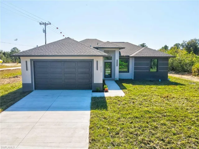 Single story home with stucco siding, driveway, a front lawn, a shingled roof, and a garage
