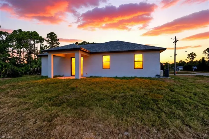 Back of property with stucco siding, a yard, and a patio