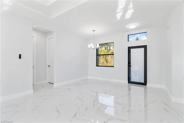 Foyer featuring light marble finish floors and a chandelier
