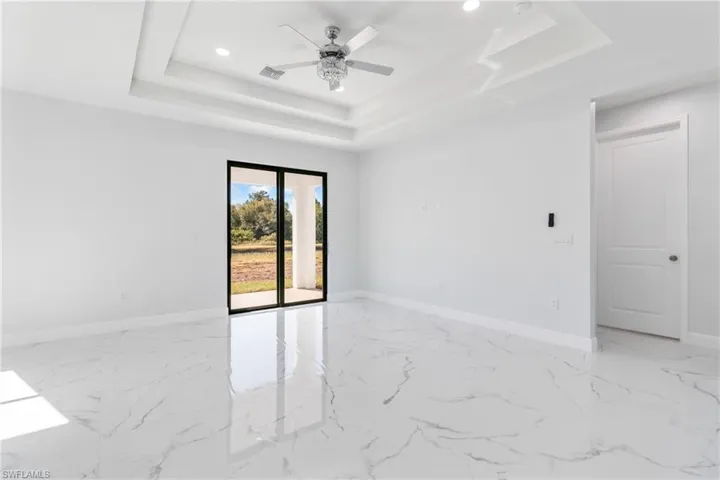 Spare room featuring recessed lighting, light marble finish flooring, a raised ceiling, and ceiling fan