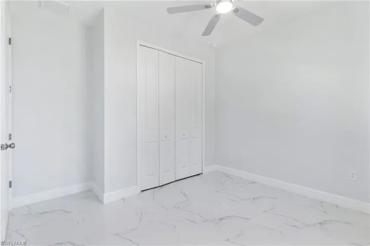 Unfurnished bedroom with light marble finish floors, a closet, and ceiling fan