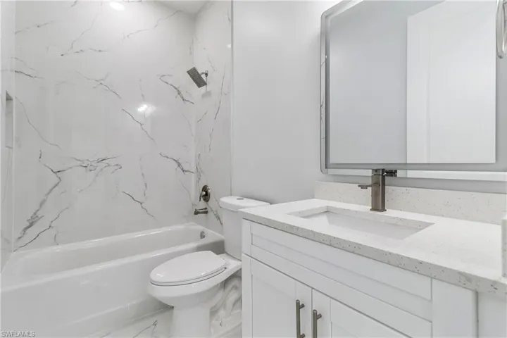Full bath featuring vanity,  shower combination, and marble finish flooring