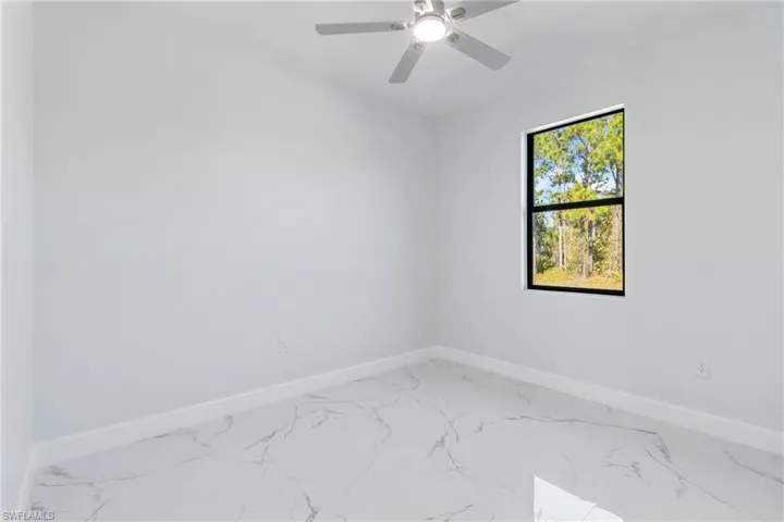 Empty room with light marble finish flooring and a ceiling fan