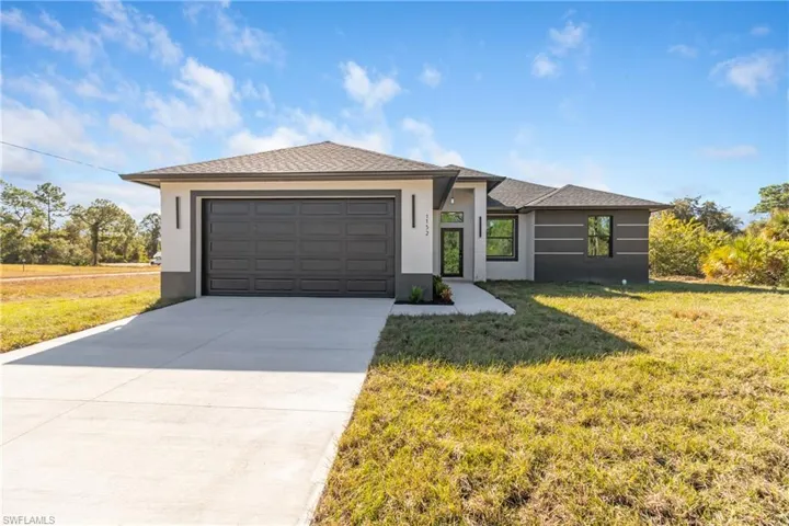 Prairie-style home with stucco siding, a front lawn, concrete driveway, and an attached garage