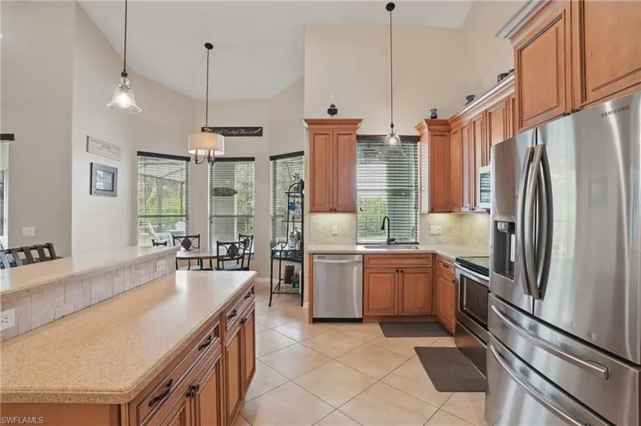 Kitchen with stainless steel appliances, a sink, light countertops, decorative backsplash, and light tile patterned floors