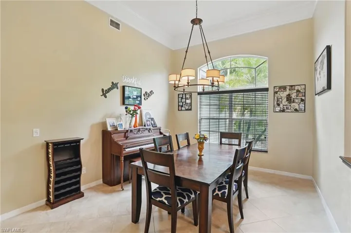 Dining room featuring light tile patterned flooring, ornamental molding, and a chandelier