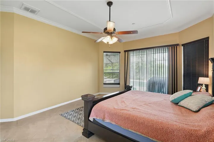 Bedroom with crown molding, light tile patterned floors, and a ceiling fan