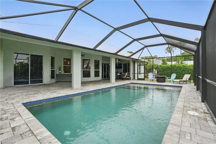 Swimming pool with a patio area, ceiling fan, and glass enclosure