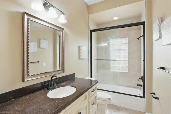 Bathroom featuring vanity, toilet, enclosed tub / shower combo, and tile patterned flooring