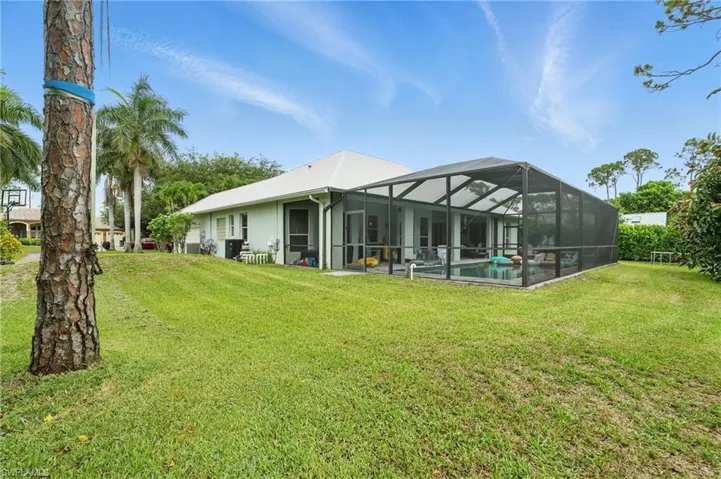 Rear view of house with an outdoor pool, a lawn, and glass enclosure