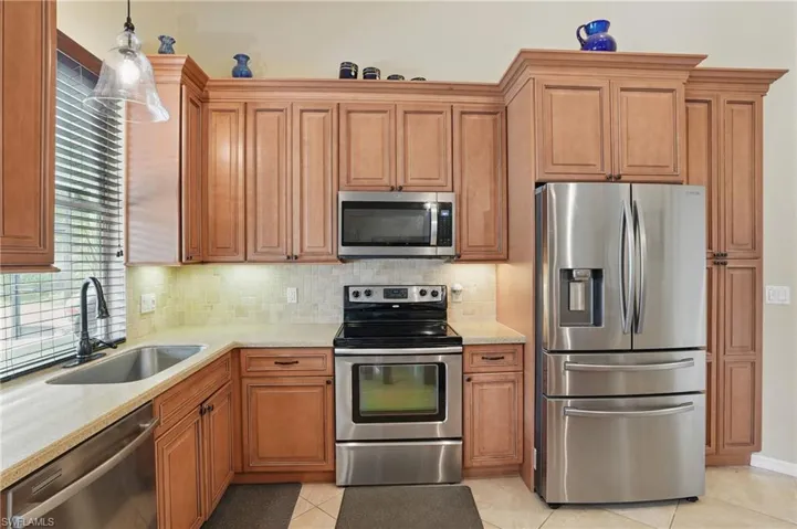 Kitchen with appliances with stainless steel finishes, a sink, tasteful backsplash, and light tile patterned floors