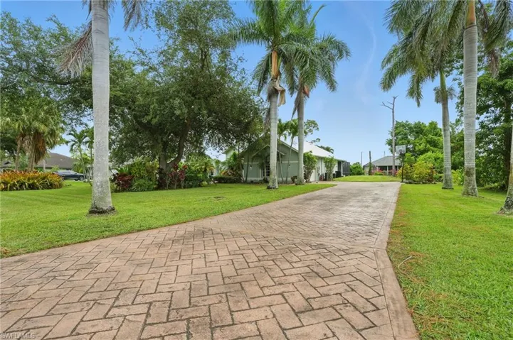 View of front of property with a front yard and decorative driveway