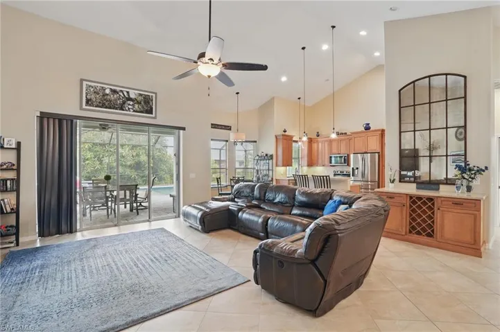 Living area with ceiling fan, high vaulted ceiling, light tile patterned floors, and recessed lighting