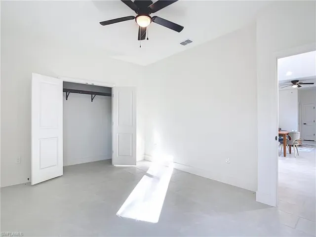 Bright room featuring light-colored tile flooring, a black ceiling fan with an integrated light, and a double-door closet with an interior hanging rod