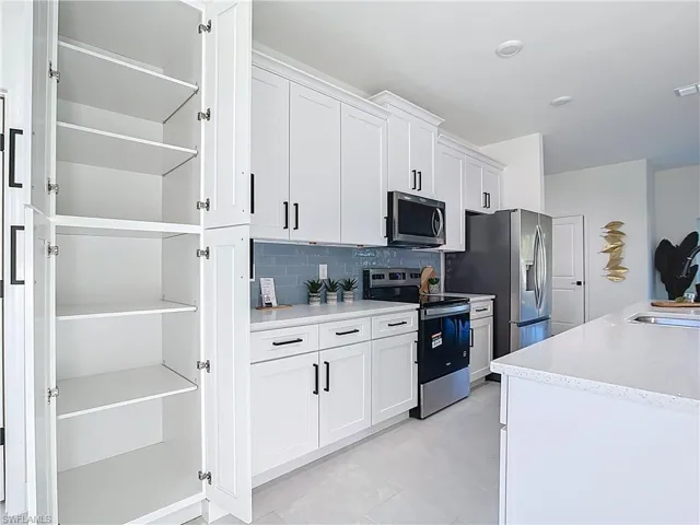 White shaker cabinetry with black hardware, complementing a blue subway tile backsplash