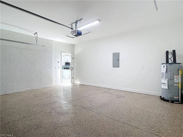 Spacious garage featuring a durable aggregate-finish floor, a garage door opener, and a water heater