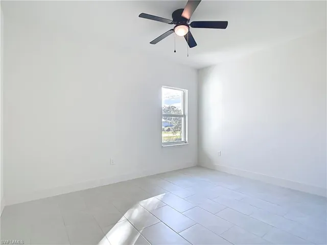Bright room with white tile flooring and a ceiling fan